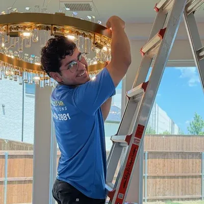Technician installing crystal chandelier from ladder — Fort Worth, TX | Goldstar Renovations